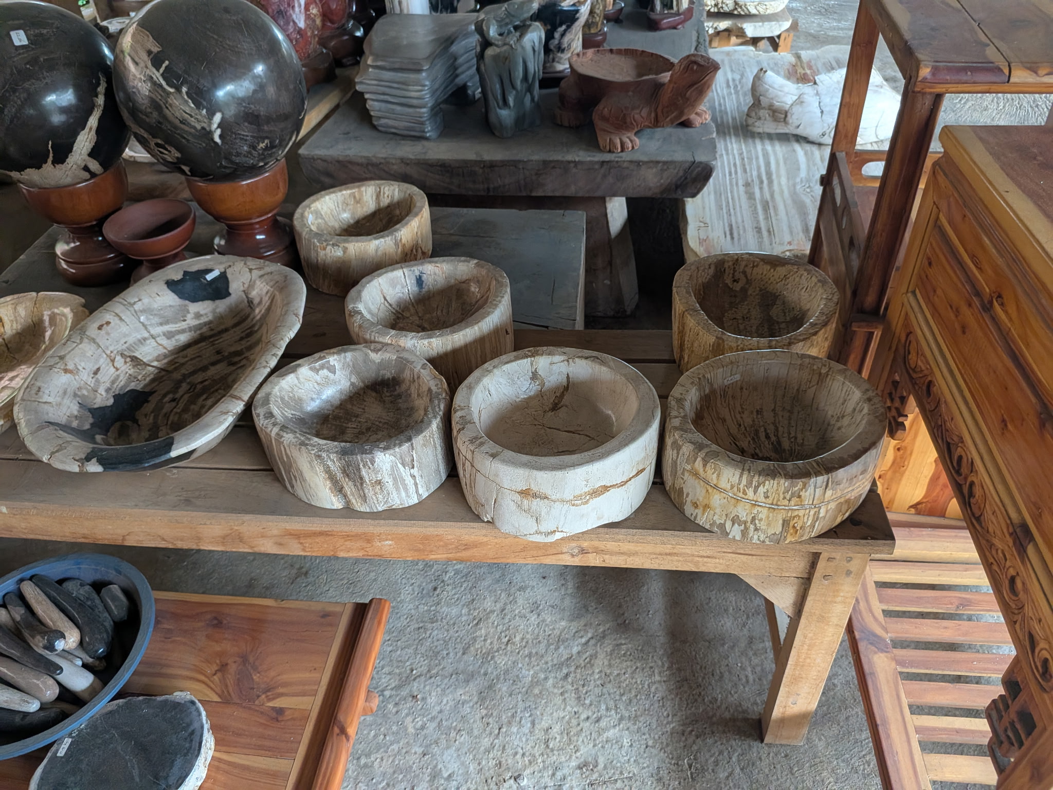 A collection of petrified wood bowls in the Java yard, showing varied sizes and mineral tones.